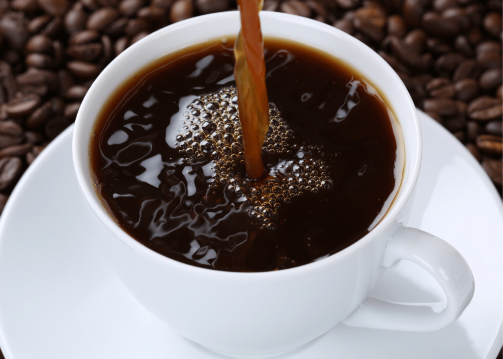how to clean a keurig 2.0, photo of a black coffee being poured into a white mug surrounded by coffee beans